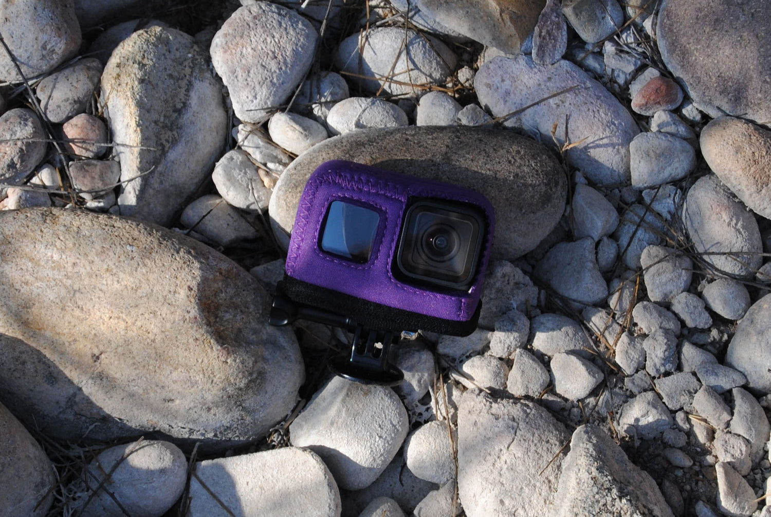 Small purple Action Skins Go Pro Camera Cover DJI on a bed of rocks